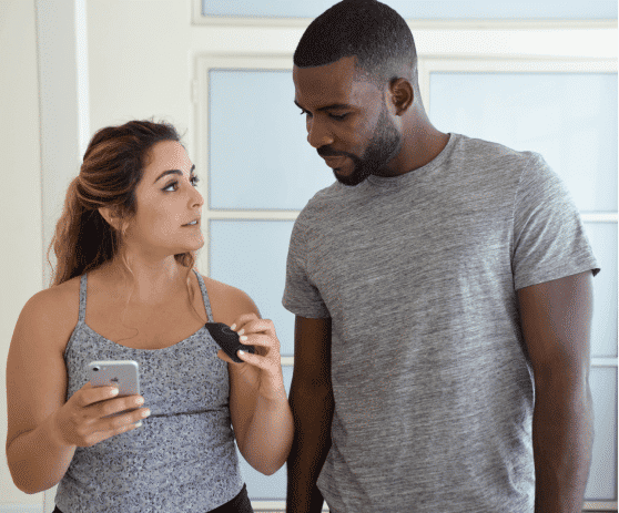 A woman with a Lumen device and a cell phone in her hand looks at a man